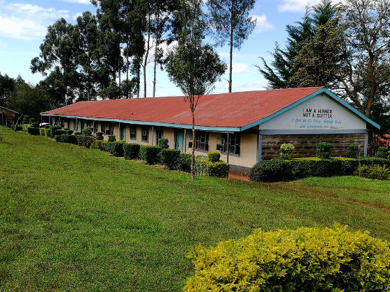 A long white single-storey building with a red corrugated roof